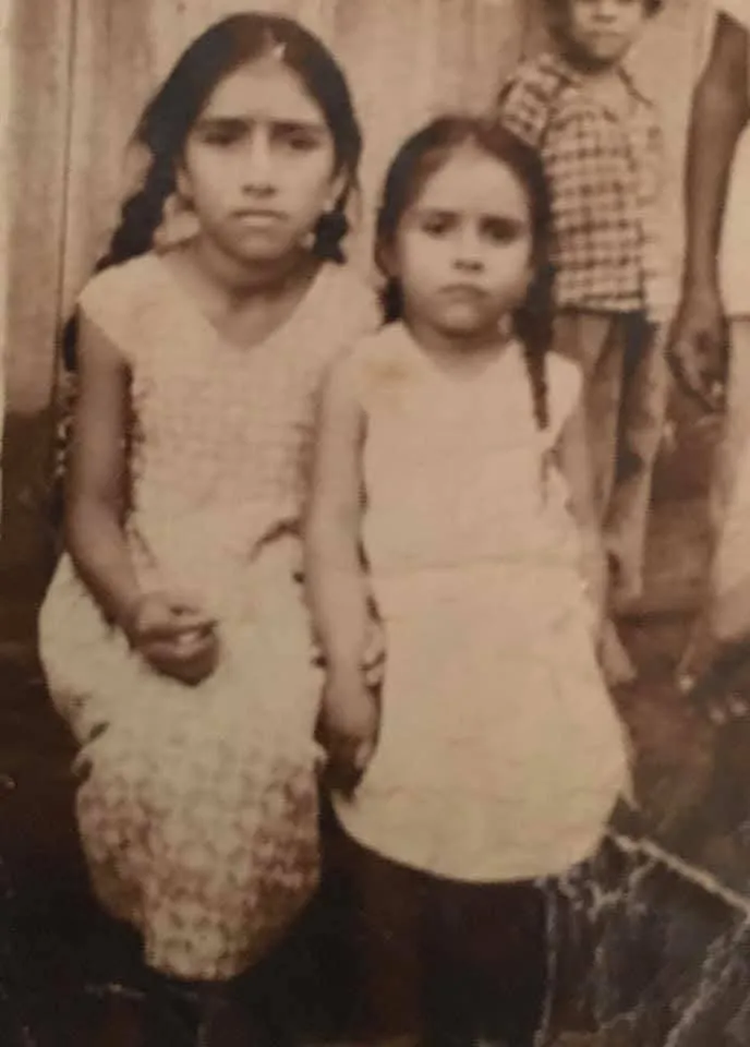 Two children, an older sibling beside a younger one, in a sepia-toned portrait