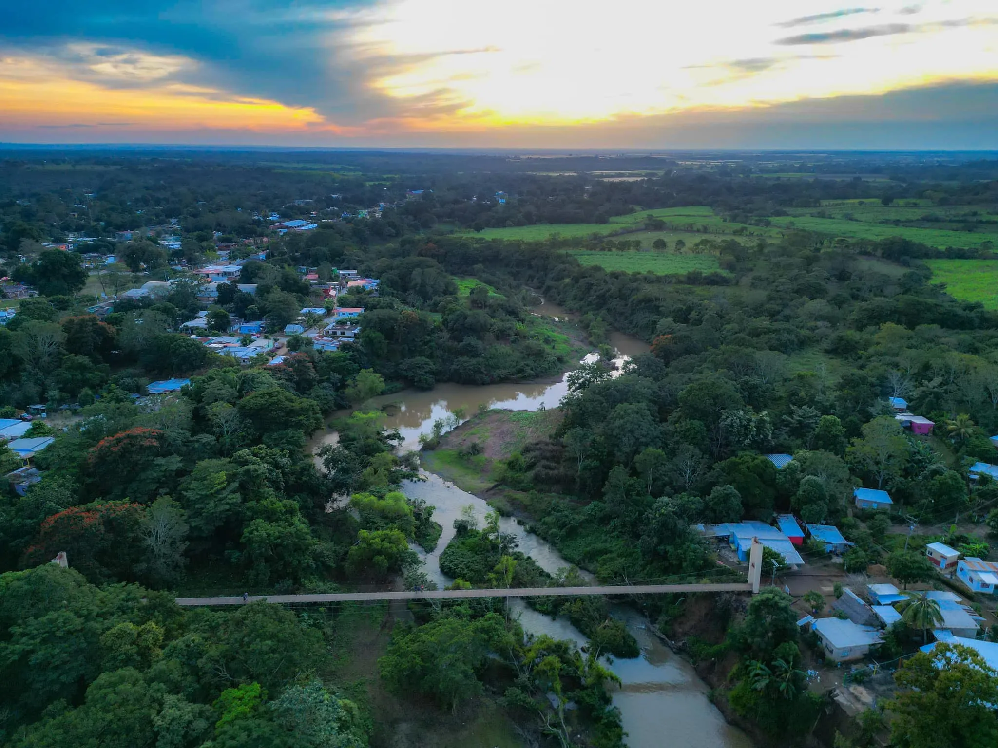 Aerial view of the community at sunset, with a river winding through green fields and homes